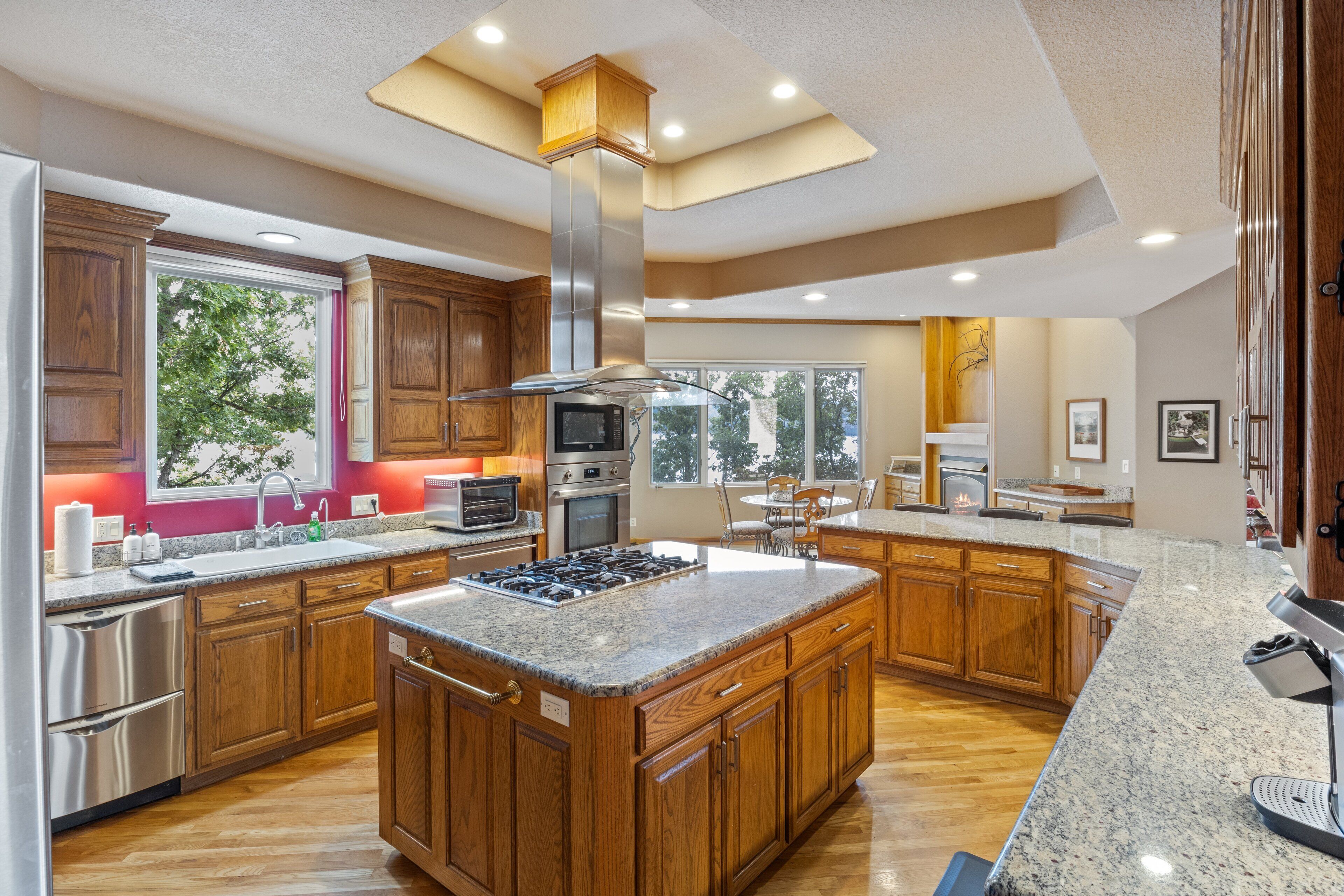 A spacious kitchen with wooden cabinets, a large island, stainless steel appliances, and a view of the outdoors.