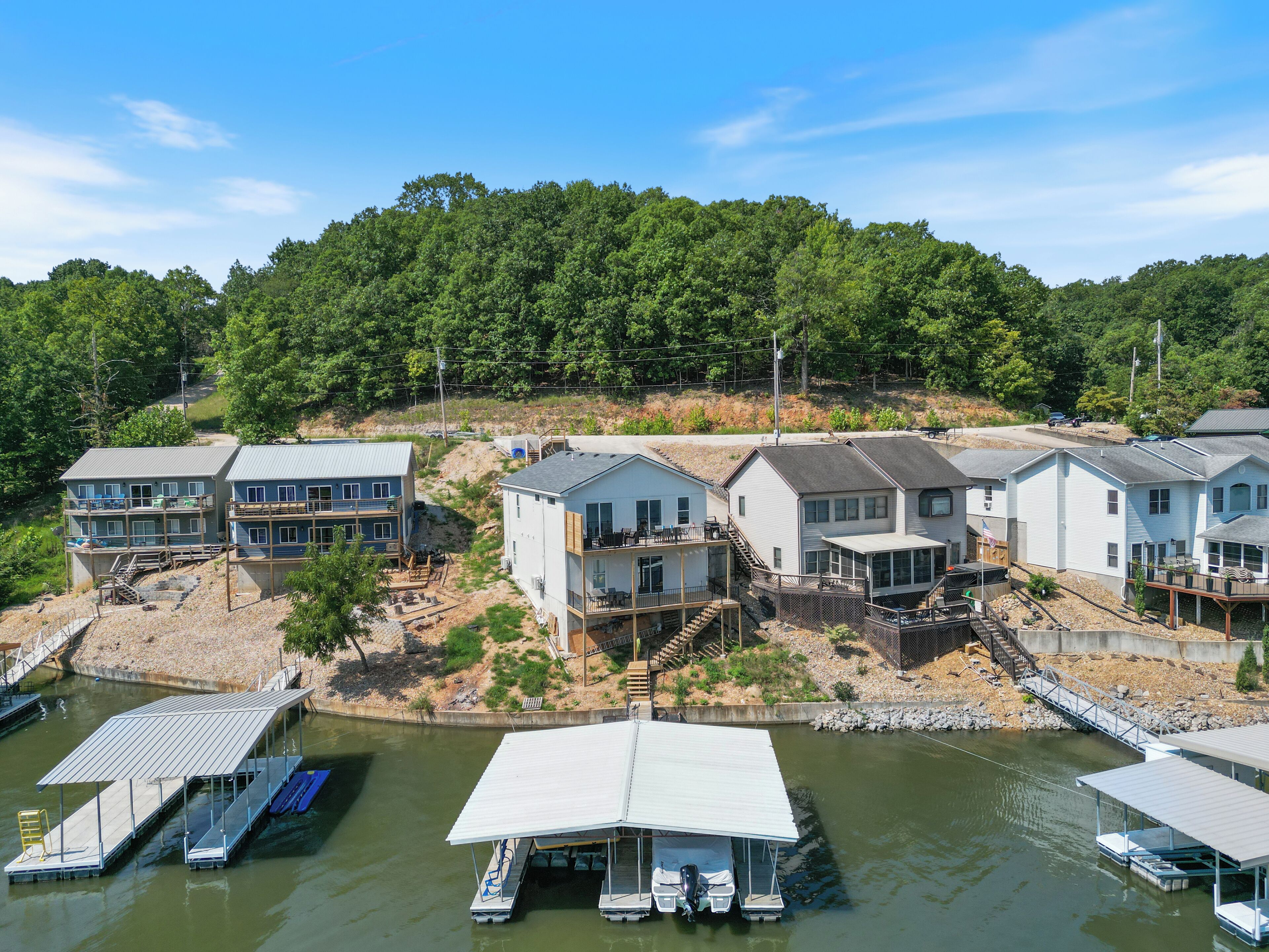 A lakeside property with multiple houses, docks, and a forested hillside.