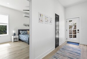 A modern bedroom with a bed, bedside table, and a door with a glass panel. - Expansive Deck, Private Dock, Boat Slip and Stunning Views (Climax Springs)