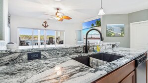 A kitchen with a large island, a ceiling fan, and a view of the outdoors. - Island Life! Amazing Balcony-views-pool and Patio (Rocky Mount)