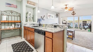 A modern kitchen with a dishwasher, wooden cabinets, and a granite countertop. - Island Life! Amazing Balcony-views-pool and Patio (Rocky Mount)