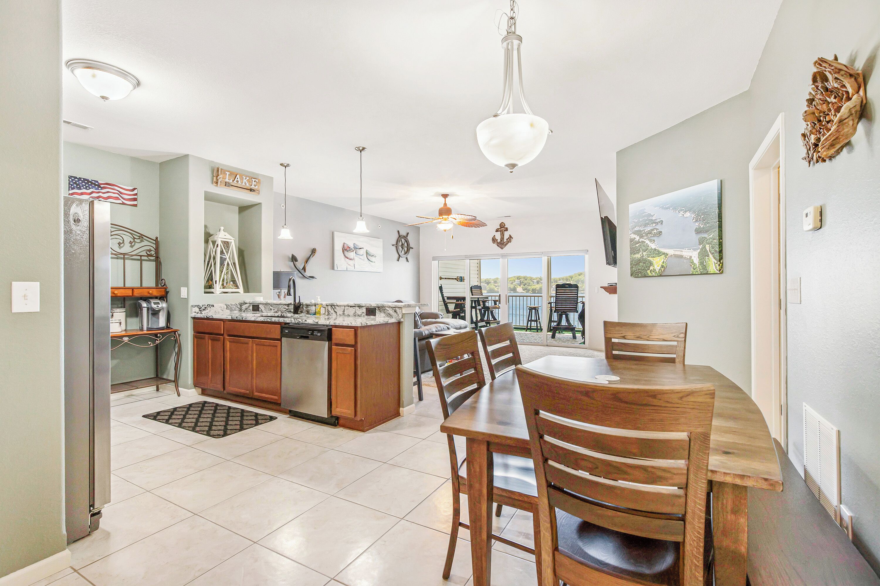 A spacious kitchen with a dining area, featuring a large island, wooden cabinets, and a view of the outdoors.