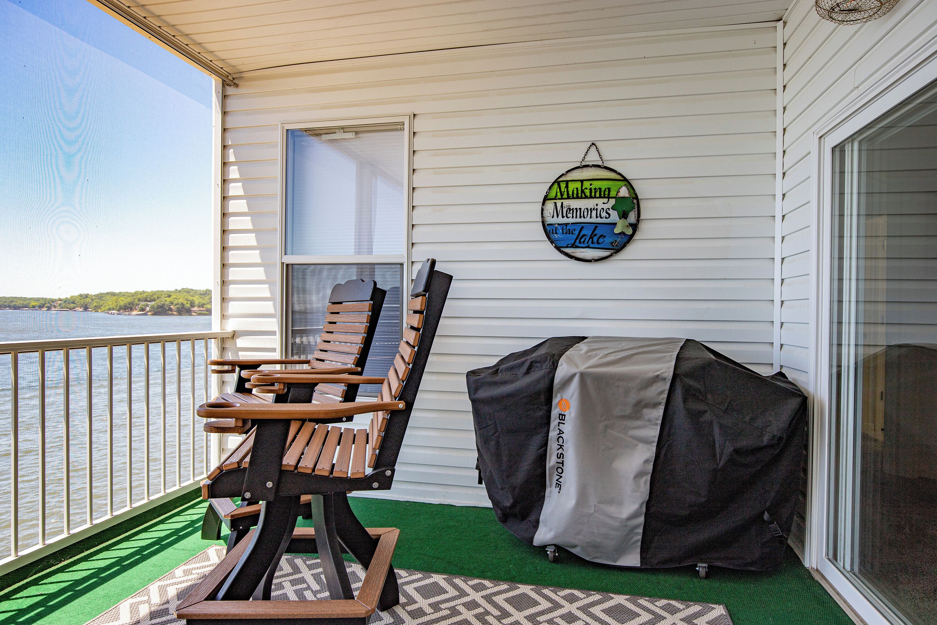 Area salotto esterna coperta con barbecue e un cartello che dice 'Making Memories at the Lake'.