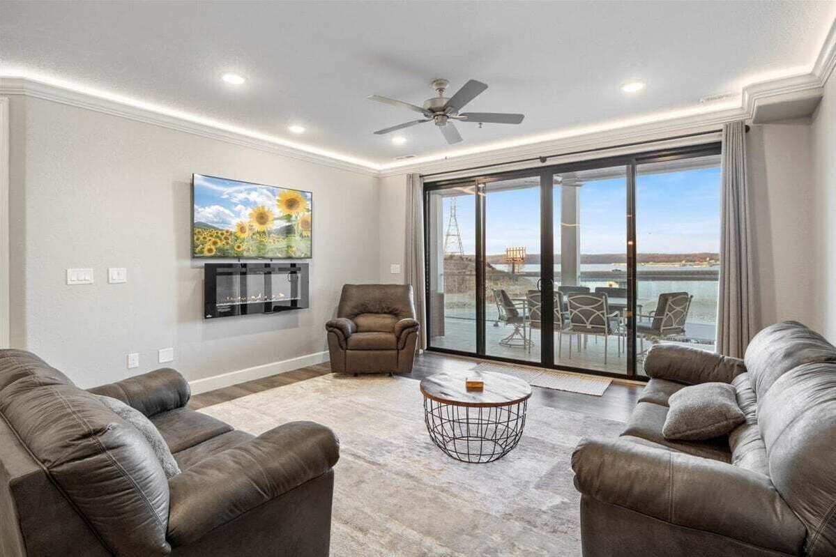 Ein großzügiges Wohnzimmer mit Ledersofas, einem Couchtisch und einem großen Fenster mit Blick ins Freie.