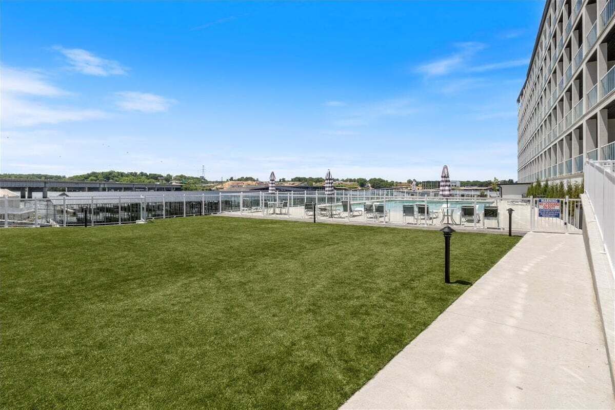 A hotel with a grassy lawn, a pool area, and a modern building with large windows.