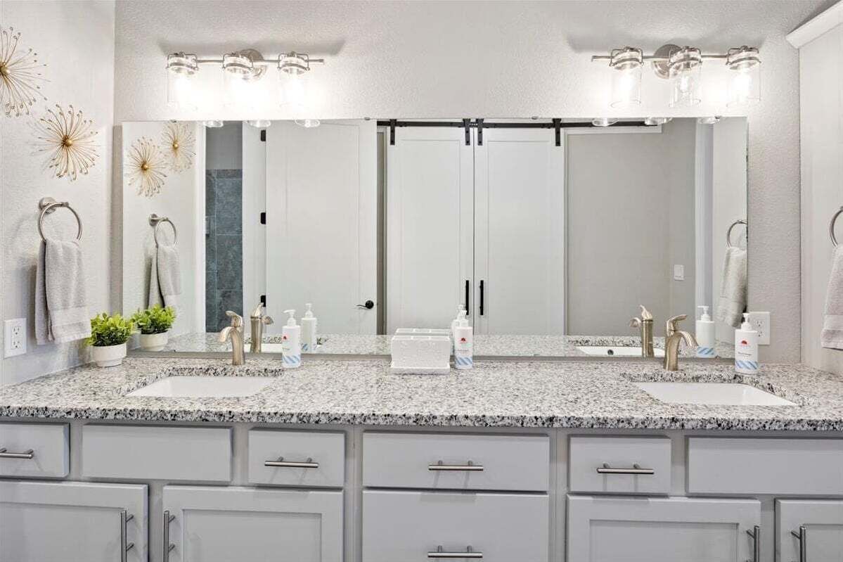 Een badkamer met twee wastafels, een grote spiegel en een aanrecht met toiletartikelen.