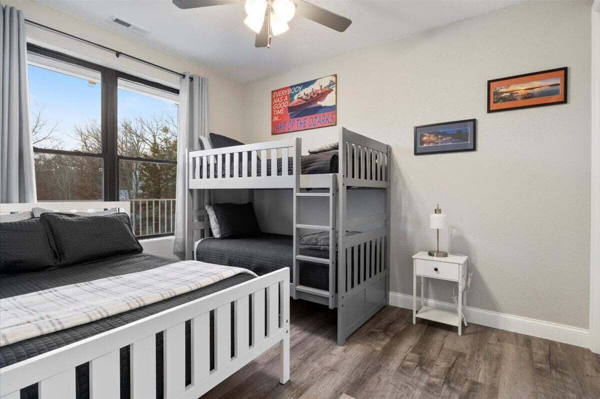 Une chambre avec des lits superposés, une petite table de chevet et une fenêtre avec des rideaux.
