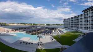 Un hôtel moderne doté d’une piscine sur le toit, de nombreux balcons et offrant une vue sur le paysage environnant.