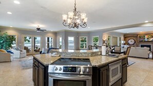A spacious kitchen with a large island, built-in oven, and a chandelier.