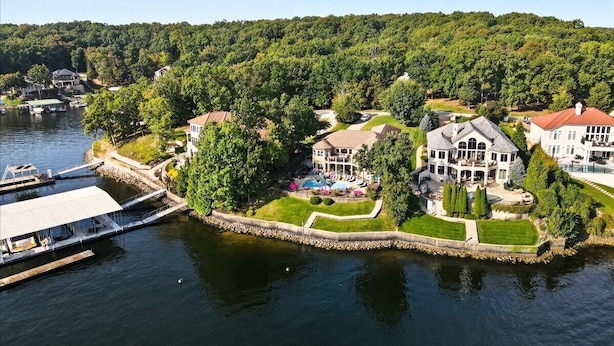 A lakeside property with multiple houses, a dock, and a well-maintained lawn.