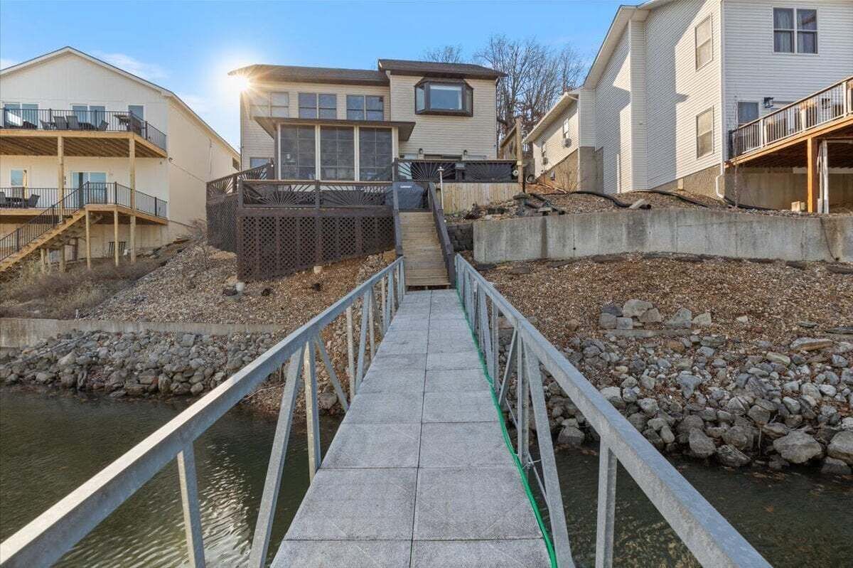 Un ponte in cemento che conduce a una casa con un balcone e una finestra al secondo piano.