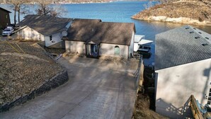 A residential area with a driveway leading to a house with a satellite dish, a garage, and a view of a lake.
