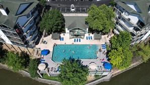 An aerial view of a hotel with a swimming pool surrounded by trees, a covered seating area, and a parking lot. - Breathtaking Views - Two Pools - Enclosed Balcony (Lake Ozark)