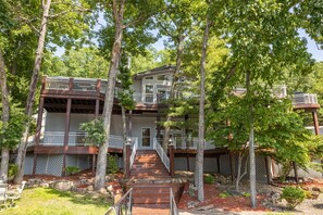A multi-story building with a wooden exterior, multiple balconies, and a staircase leading to the entrance.