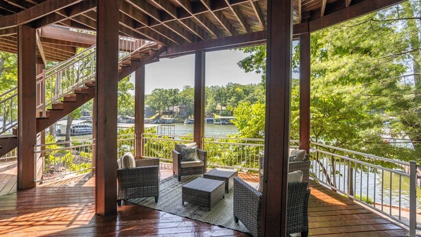 A covered outdoor deck with wicker furniture, a staircase, and a view of a lake with boats. - Kahokee Trail Lodge-pedal Boat, and Nearby Restos (Rocky Mount)