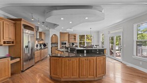 A spacious kitchen with wooden cabinets, a stainless steel refrigerator, and a large island. - Kahokee Trail Lodge-pedal Boat, and Nearby Restos (Rocky Mount)