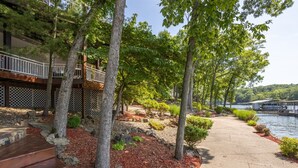 A wooden deck with steps leading to a covered area, surrounded by trees and a pathway beside a body of water. - Kahokee Trail Lodge-pedal Boat, and Nearby Restos (Rocky Mount)