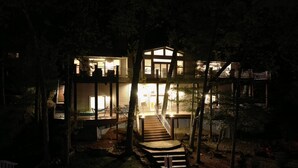 A multi-level house with a staircase leading to the upper floor, surrounded by trees and a well-lit exterior. - Kahokee Trail Lodge-pedal Boat, and Nearby Restos (Rocky Mount)