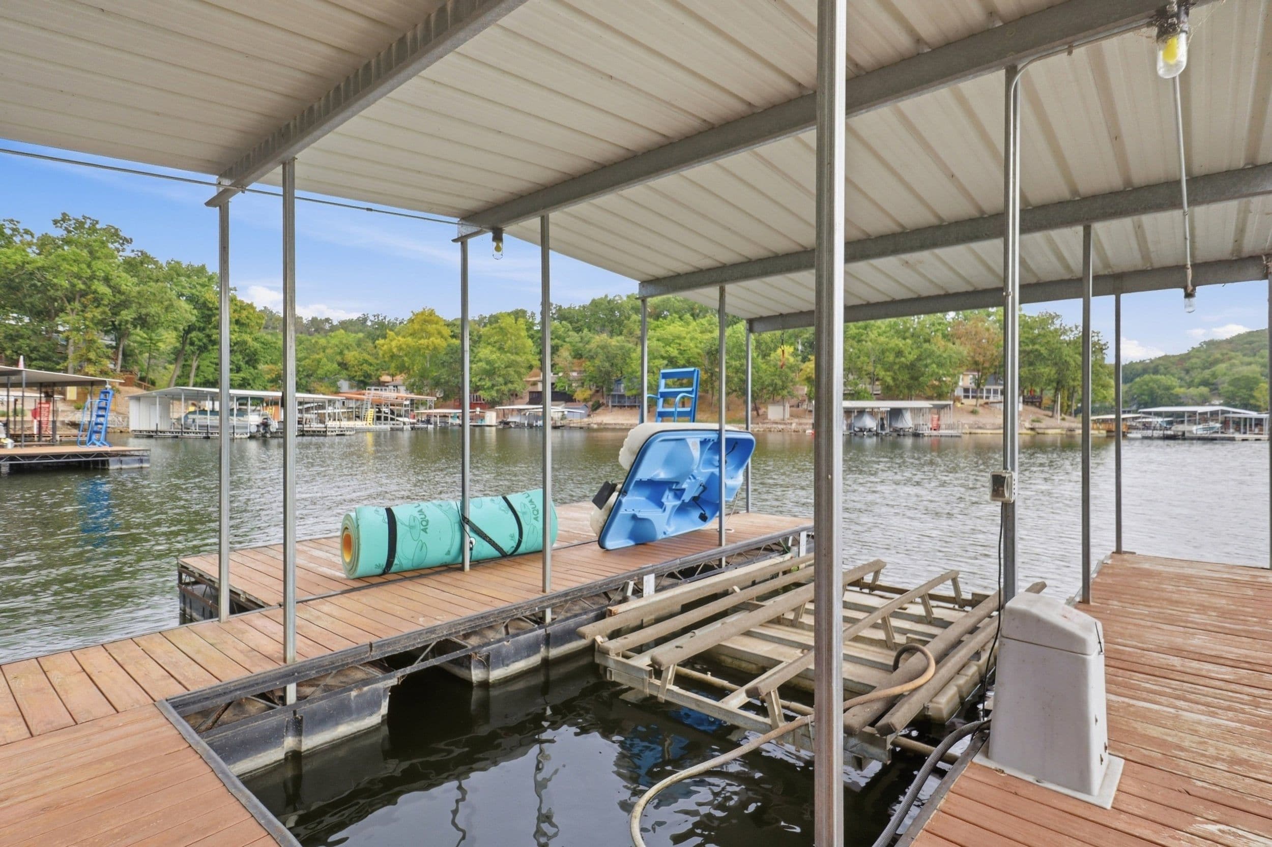 Un muelle cubierto con cubierta de madera, una silla azul y un kayak.