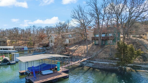 A dock with a covered seating area and a boat, surrounded by houses and trees. - Fishing, Boat Slip, Morning Coffee, Picturesque View (Sunrise Beach)