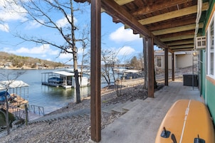 Uma área de doca coberta com um barco, vista para o lago e um edifício com fachada verde.