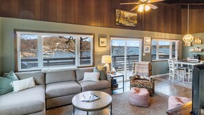 A cozy living room with a sofa, ottoman, coffee table, and a television. - Fishing, Boat Slip, Morning Coffee, Picturesque View (Sunrise Beach)