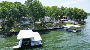 A houseboat docked at a marina with a small dock and a covered area. - Unforgettable Views & Lakefront Firepit Nights (Sunrise Beach)