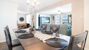 A dining area with a wooden table, dark chairs, a chandelier, and a view of the outdoors. - Unforgettable Views & Lakefront Firepit Nights (Sunrise Beach)