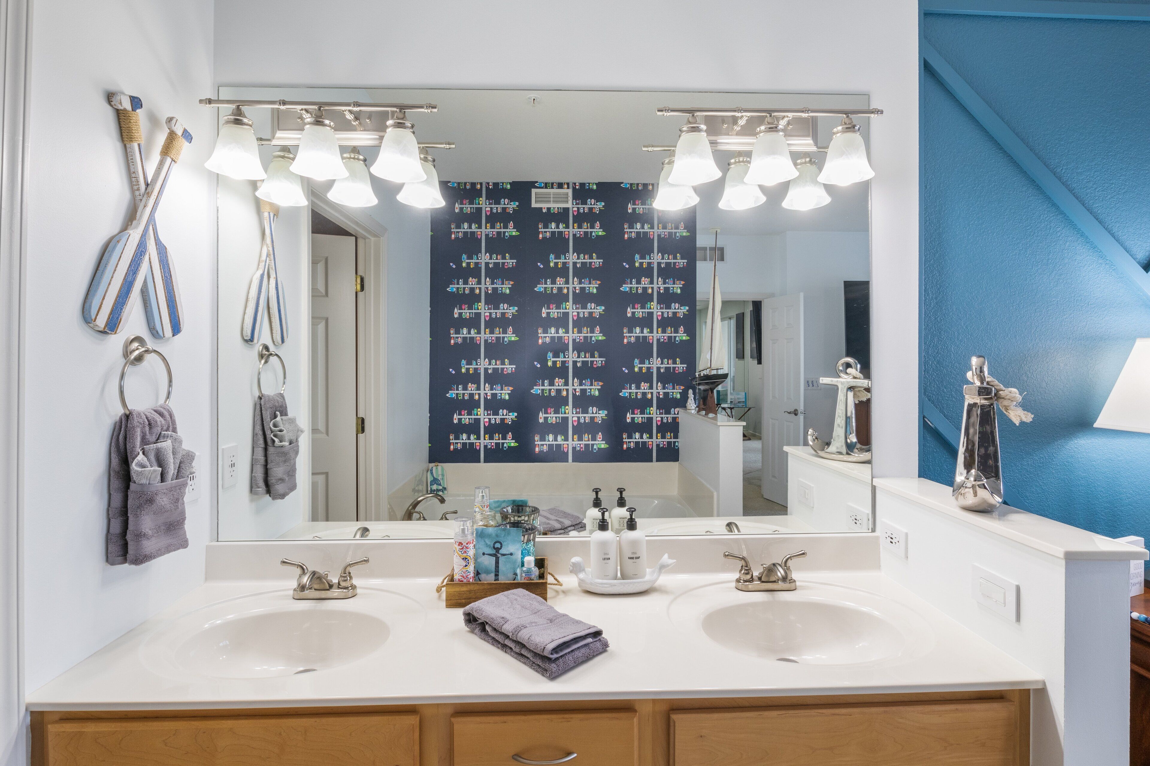 A bathroom with two sinks, a large mirror, and a blue accent wall.