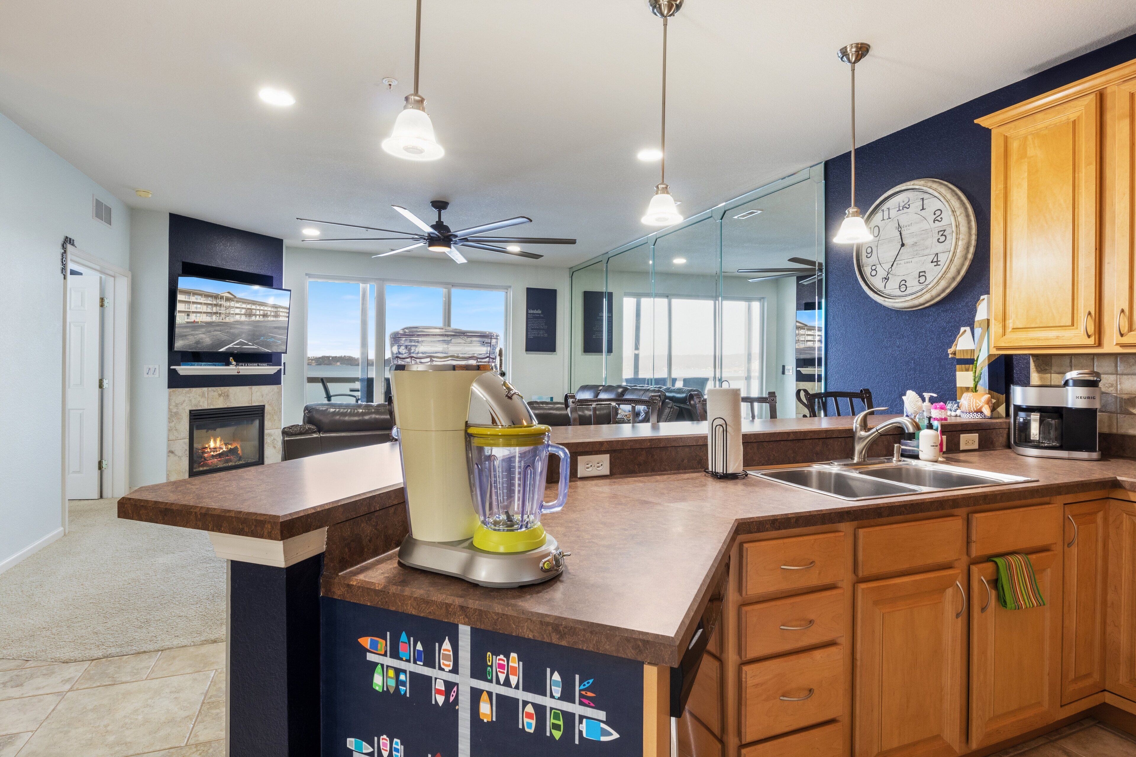 Una cocina moderna con una isla grande, cafetera integrada y vista al área de estar.