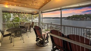 A covered deck with outdoor furniture, a view of the water, and a sunset. - Incredible Views, Spacious Deck, Private Dock, Gas Grill, Games & Cards (Gravois Mills)