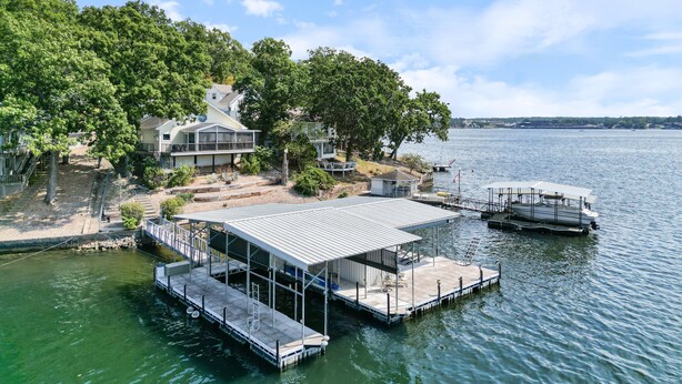 A lakeside property with a dock, a covered boat launch, and a house with a large deck. - Incredible Views, Spacious Deck, Private Dock, Gas Grill, Games & Cards (Gravois Mills)