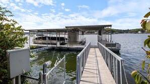A dock with a covered seating area and a boat moored nearby. - Incredible Views, Spacious Deck, Private Dock, Gas Grill, Games & Cards (Gravois Mills)