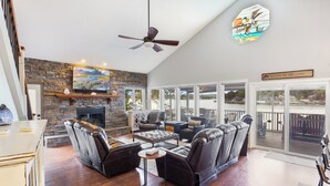 A spacious living room with a stone fireplace, leather sofas, and a large TV. - Incredible Views, Spacious Deck, Private Dock, Gas Grill, Games & Cards (Gravois Mills)