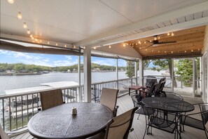 A covered outdoor seating area with tables and chairs, overlooking a body of water. - Incredible Views, Spacious Deck, Private Dock, Gas Grill, Games & Cards (Gravois Mills)