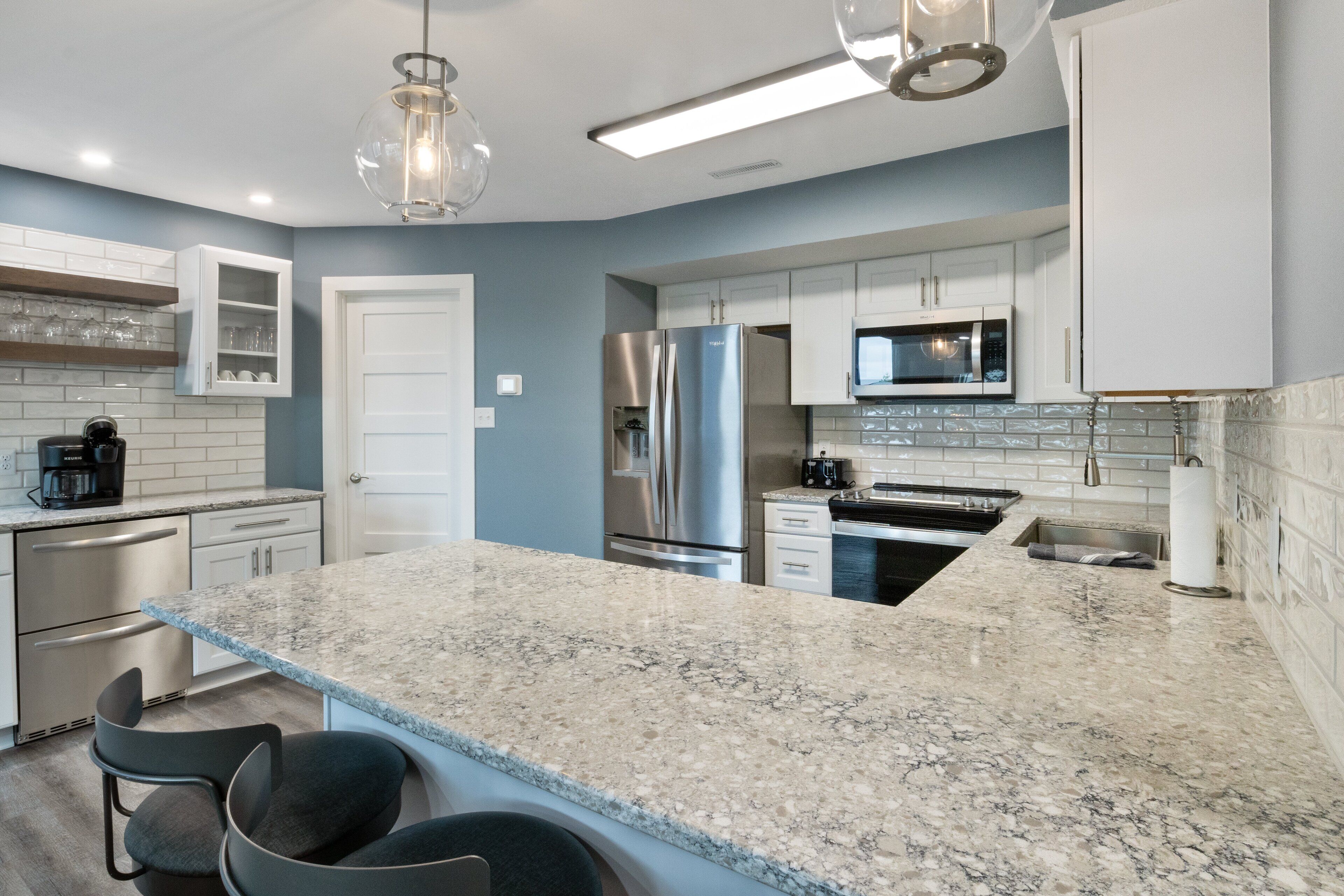 A modern kitchen with granite countertops, stainless steel appliances, and a central island with bar seating.