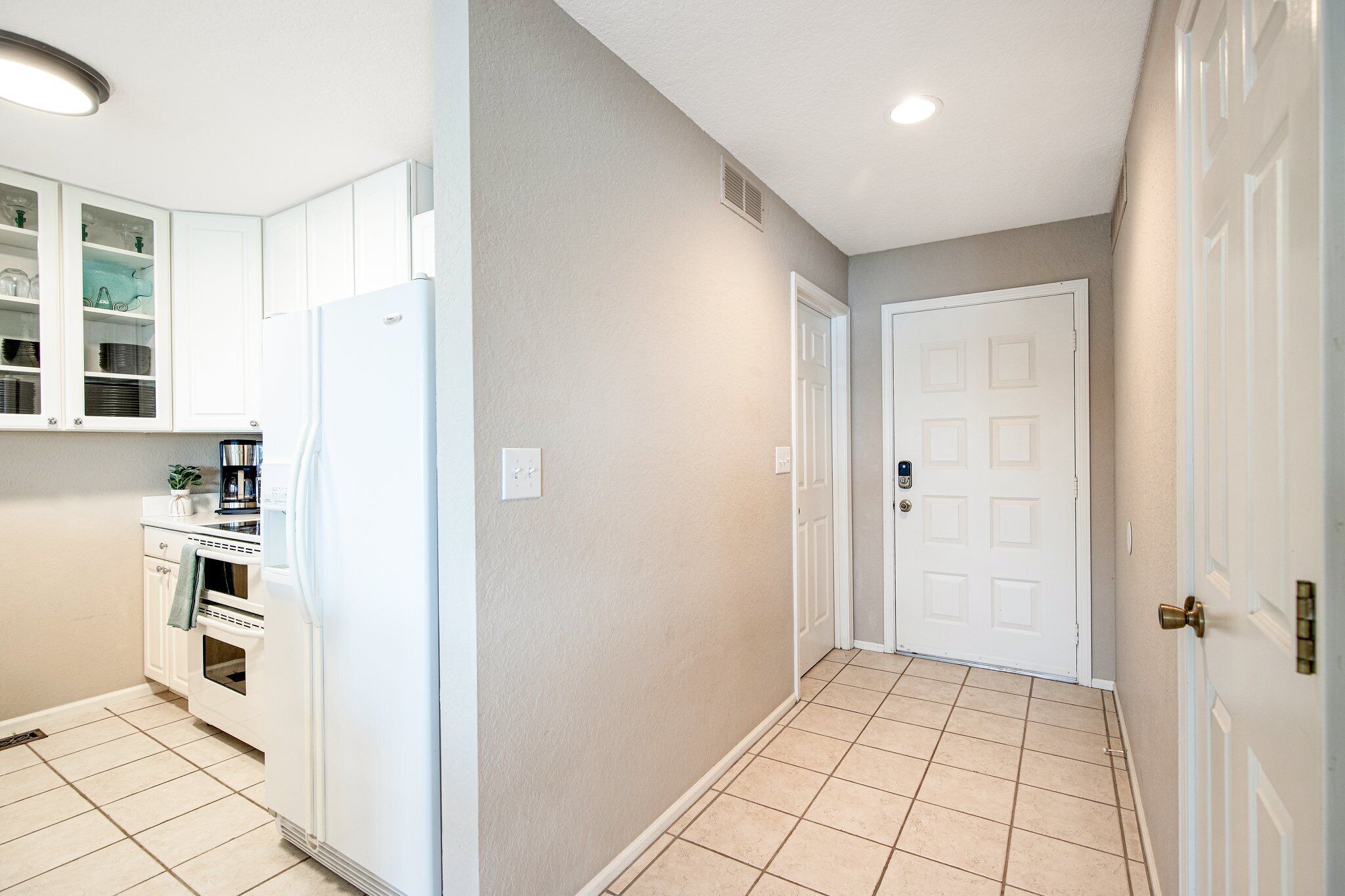 A kitchen with white cabinets, a refrigerator, and an oven.