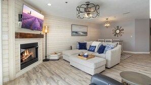 A living room with a fireplace, a television, a sofa set, and a ceiling light fixture. - Newly Updated, Amazing Views, Boat Slip & Heated Pool (Sunrise Beach)