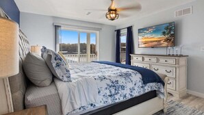 A bedroom with a large bed, a ceiling fan, a dresser, and a TV on the wall. - Newly Updated, Amazing Views, Boat Slip & Heated Pool (Sunrise Beach)