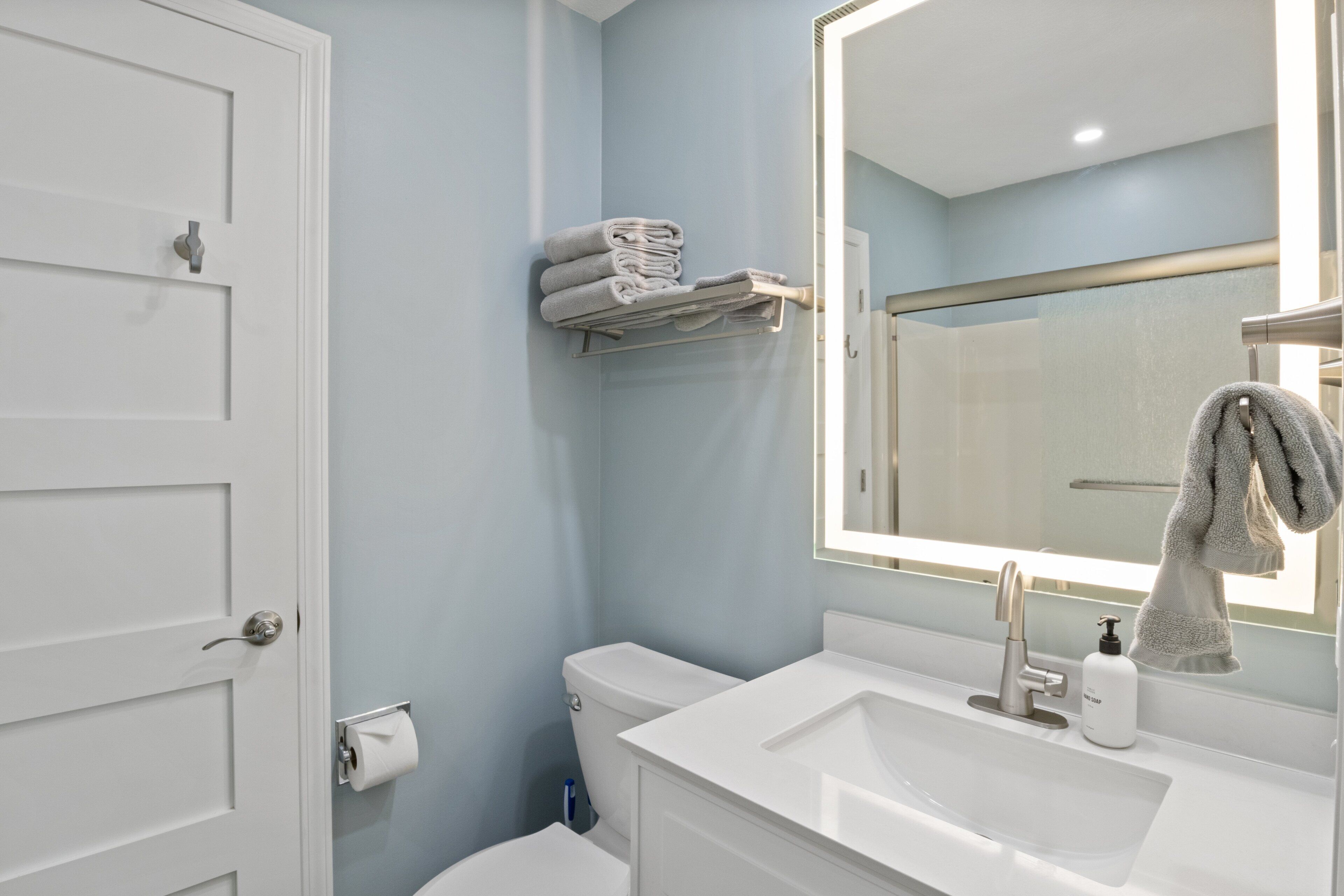 Un baño con lavabo blanco, espejo, toallero y retrete.