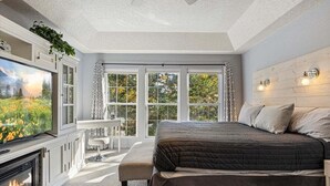 Ein Schlafzimmer mit einem großen Bett, einem Kamin und einem Fernseher.