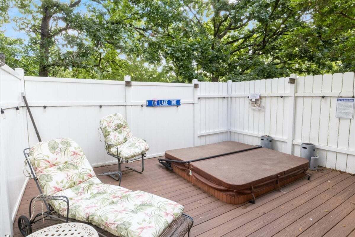 A deck with a hot tub, two lounge chairs, and a wooden deck.