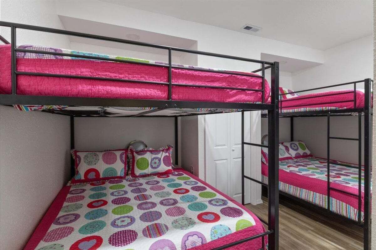 A dormitory room with bunk beds, each with a colorful quilt.