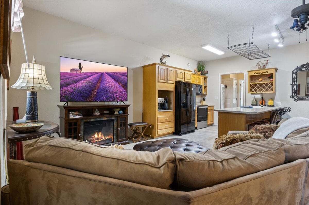 A living room with a fireplace, a television, and a kitchen area.