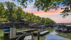 A marina with docked boats, a covered boat launch, and a wooden pier. - Stunning Views of the 7.5mm, Private Dock, Spacious Decks, Kayaks & More! (Gravois Mills)