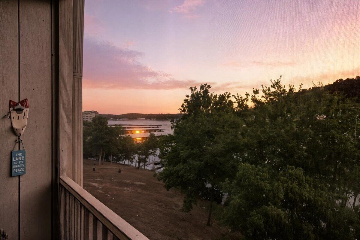 A view from a balcony overlooking a sunset, with a sign on the wall reading "THE LANE IS MY RIASSY PLACE".
