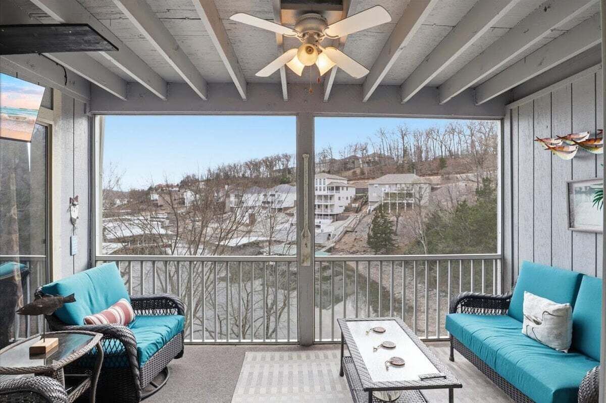 A balcony with wicker furniture, a ceiling fan, and a view of houses.