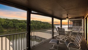 A covered outdoor seating area with a view of a river and forest. - Lazydays Pet-friendly Condo w/ Pool & Slip at 3M (Osage Beach)