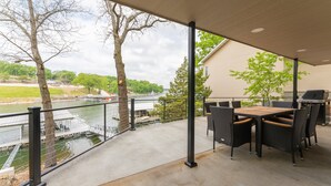 A covered patio with a view of a river, outdoor furniture, and a grill. - Amazing Lakefront Paradise With Perfect Location (Osage Beach)