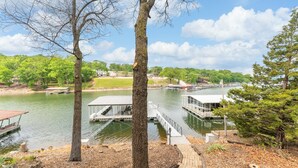 A lakeside dock with a covered seating area, a boat, and a small building. - Amazing Lakefront Paradise With Perfect Location (Osage Beach)